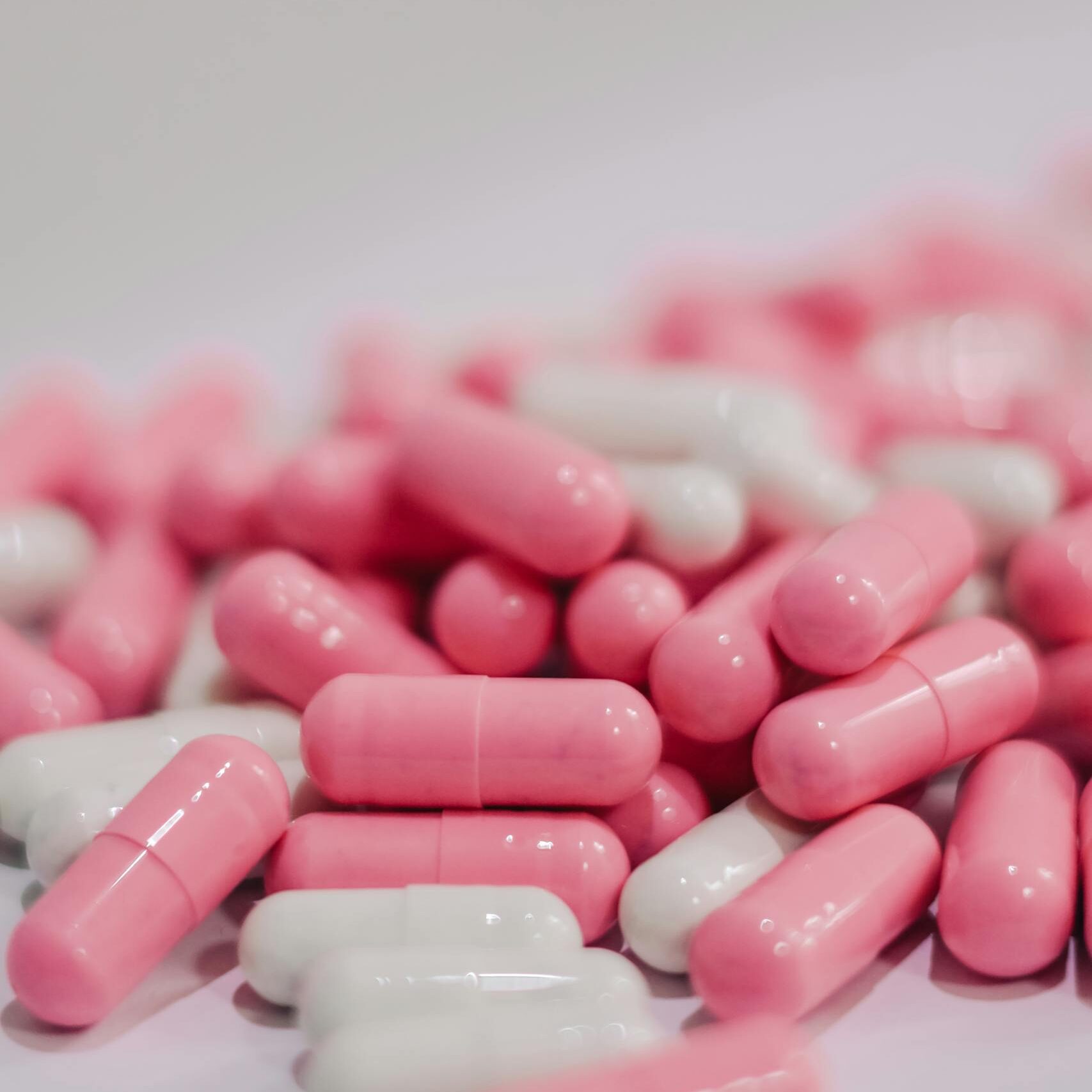 A close-up view of pink and white dietary supplement capsules on a white surface