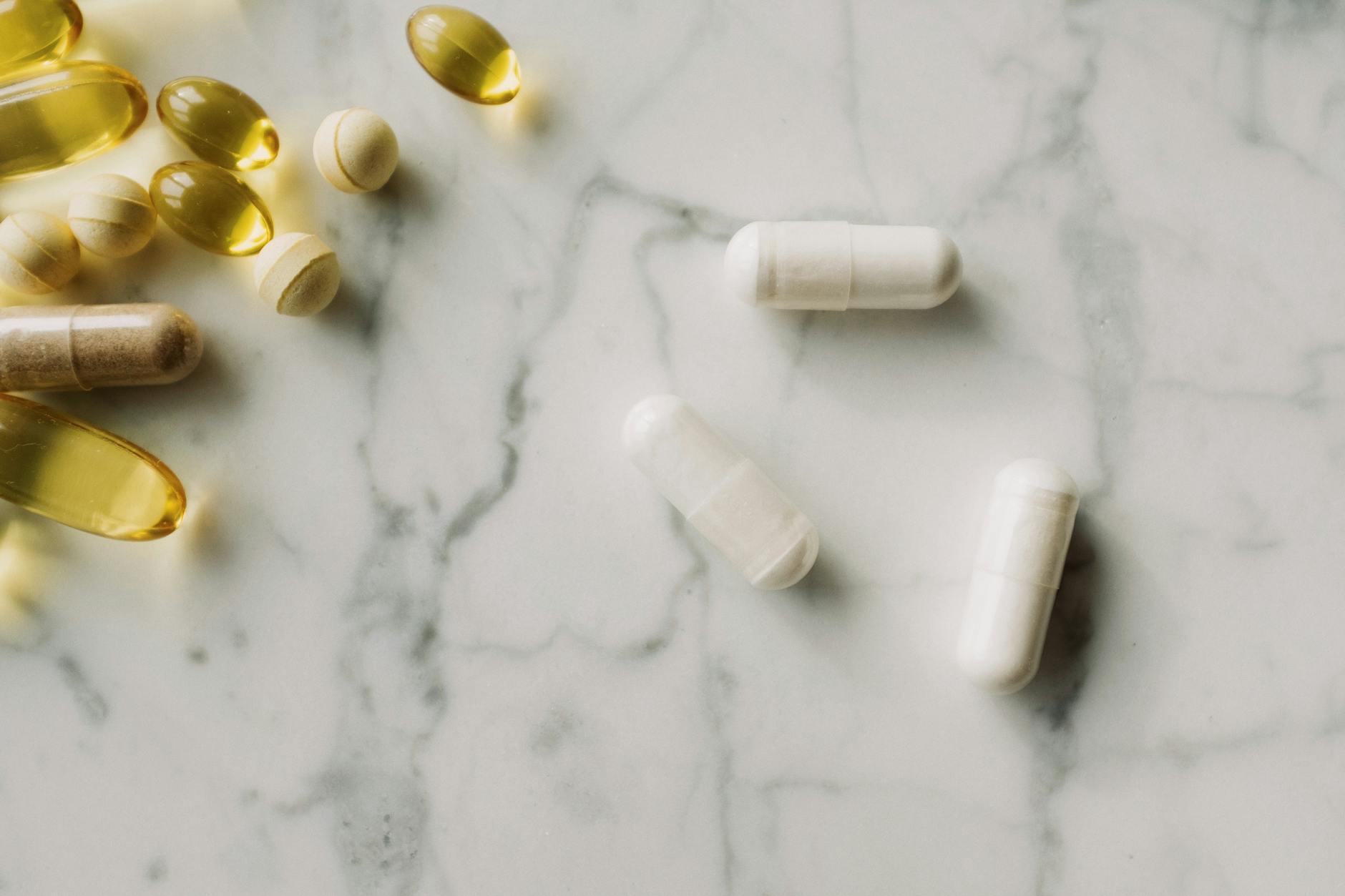 Close-up of various pills and capsules on a marble surface, ideal for healthcare themes. — Atrium Scientific Group