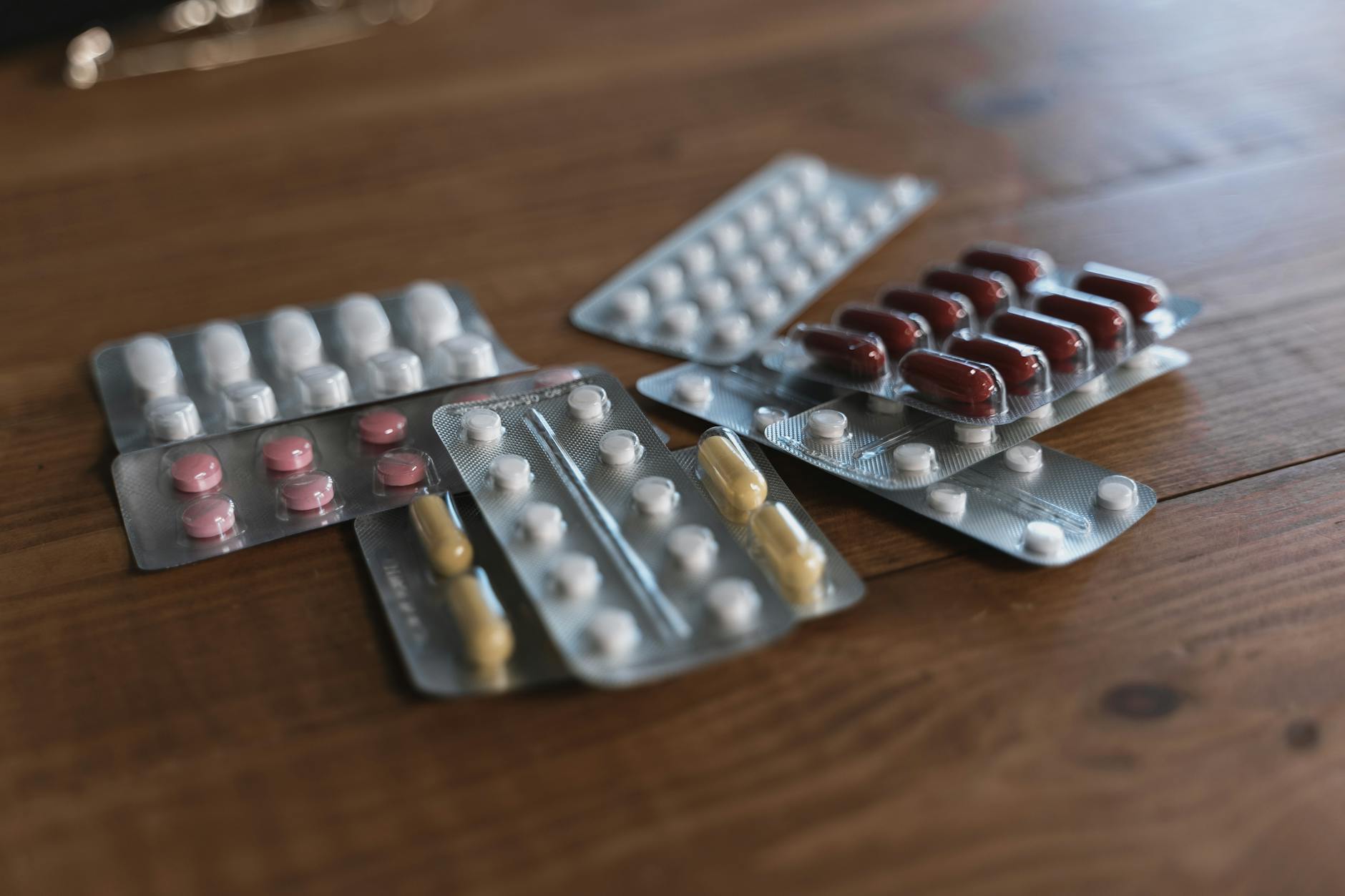 A variety of pills in blister packs displayed on a wooden surface. Ideal for health-related content. — Atrium Scientific Group