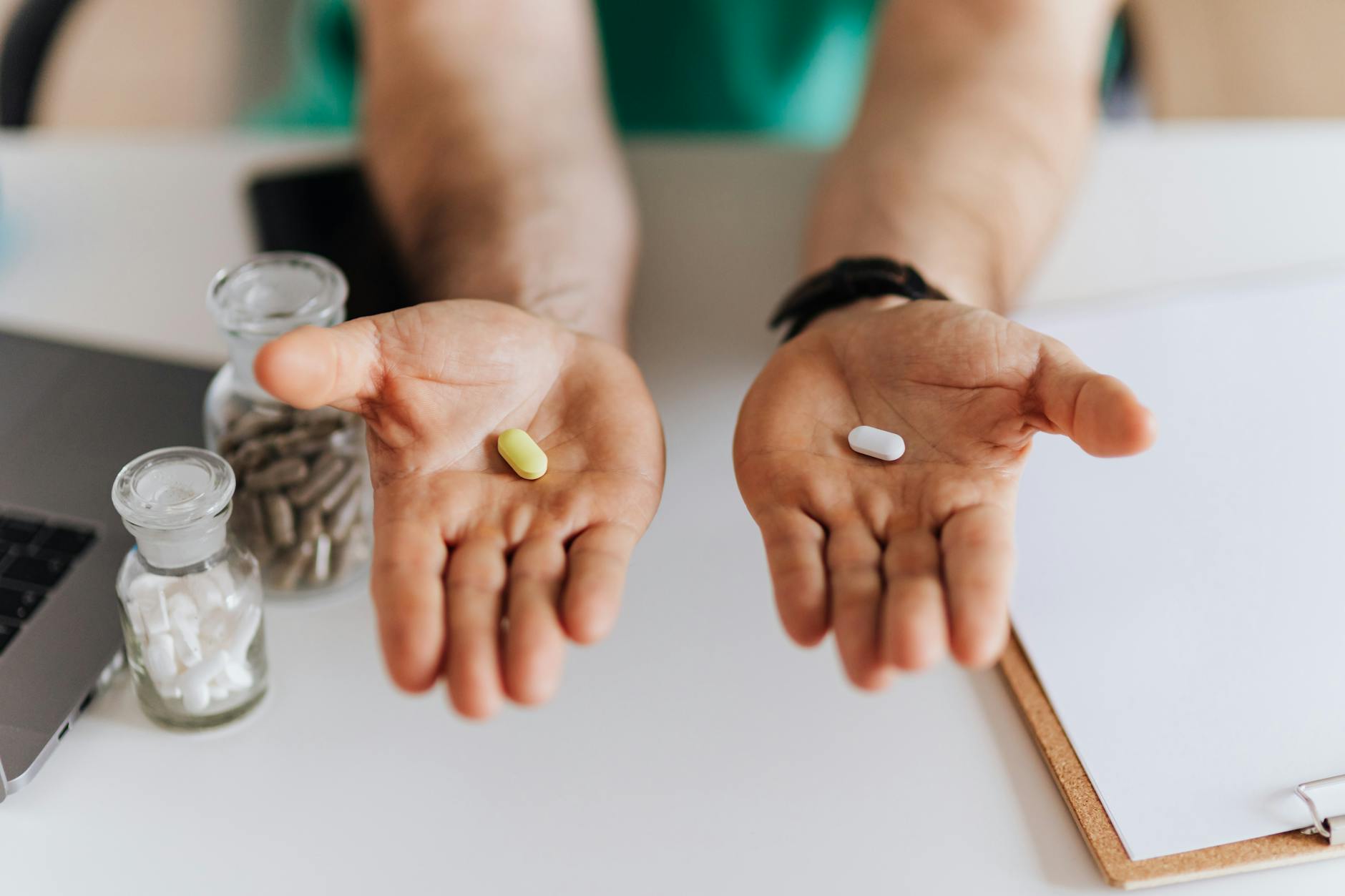 Unrecognizable male doctor sitting at table and demonstrating medicine to patient while working in modern clinic and talking with client about healthy — Atrium Scientific Group