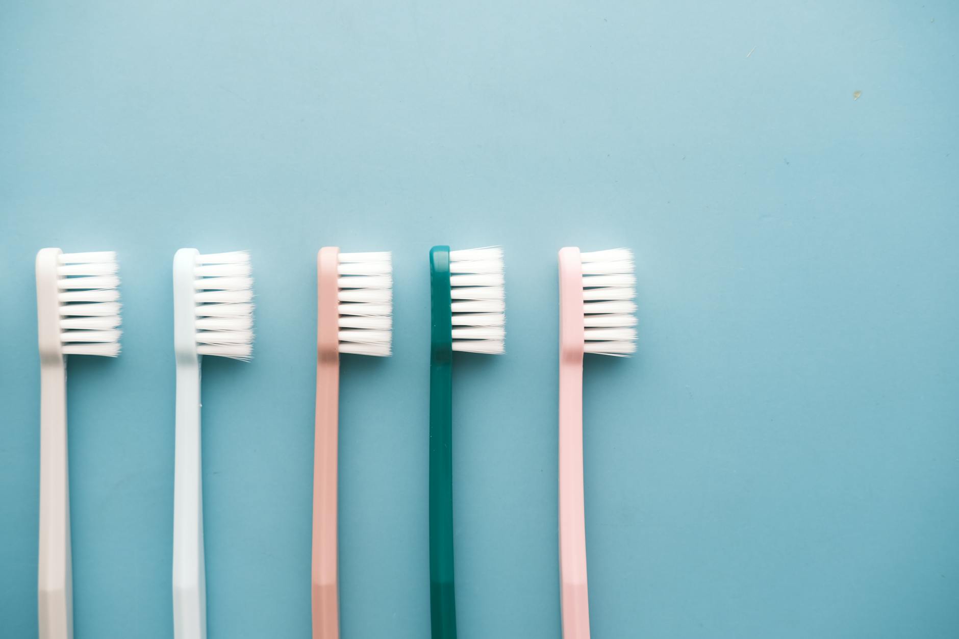A row of five colorful toothbrushes arranged on a blue background, perfect for dental care themes. — Atrium Scientific Group