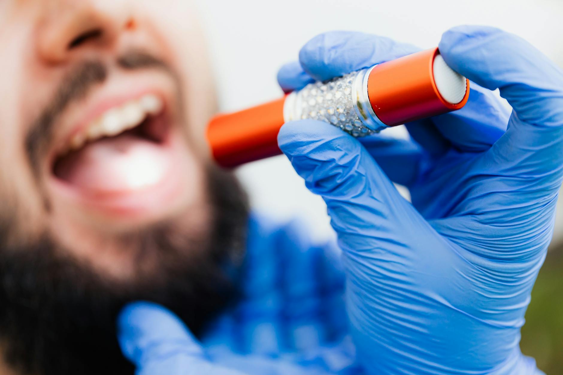 Gloved hands holding a flashlight during a dental examination, showcasing close-up detail. — Atrium Scientific Group