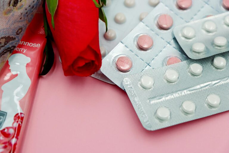 Pills and red rose on pink background, symbolizing healthcare and romance. — Atrium Scientific Group