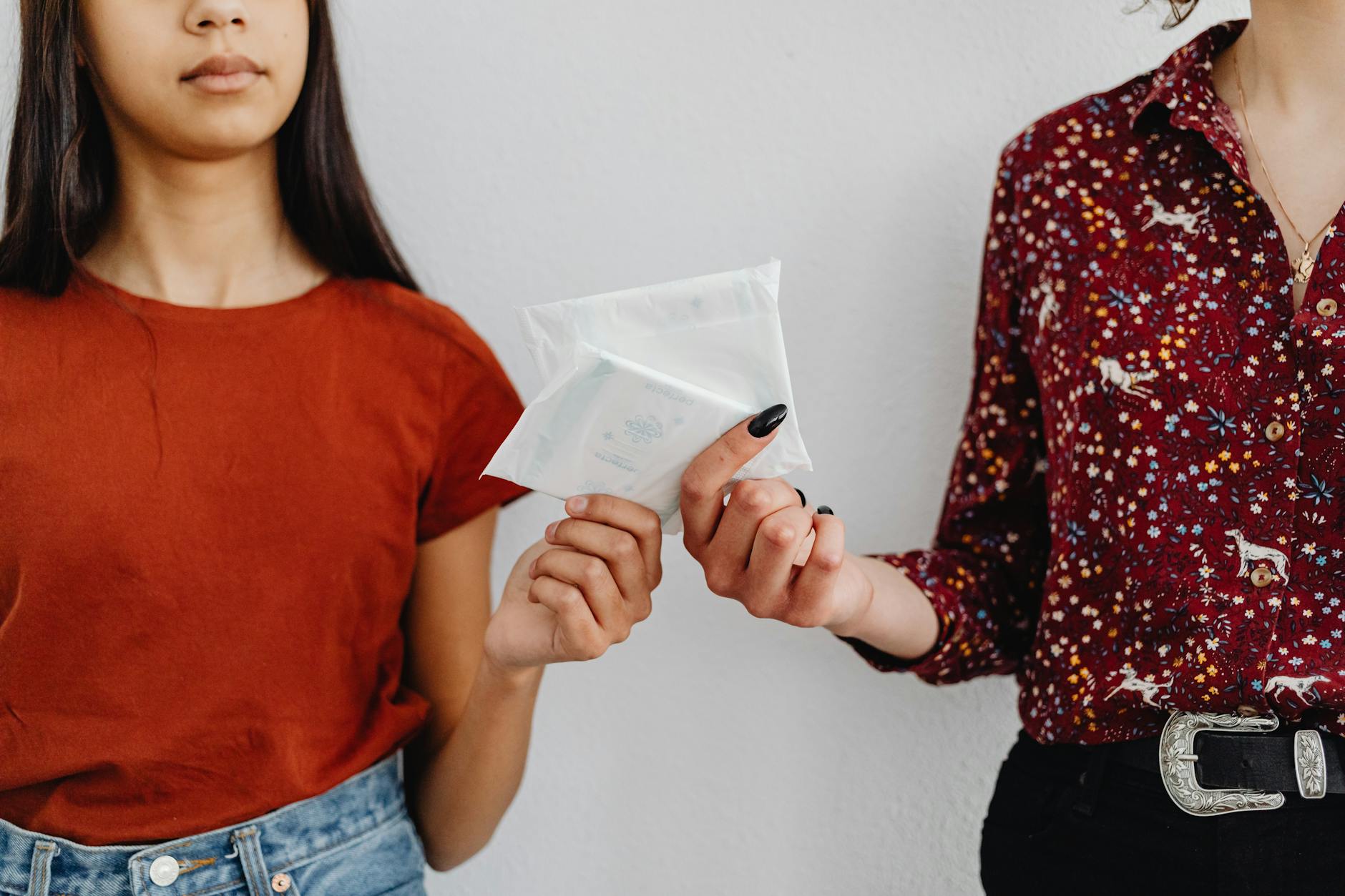 Two women exchanging sanitary pads, highlighting menstrual health awareness. — Atrium Scientific Group