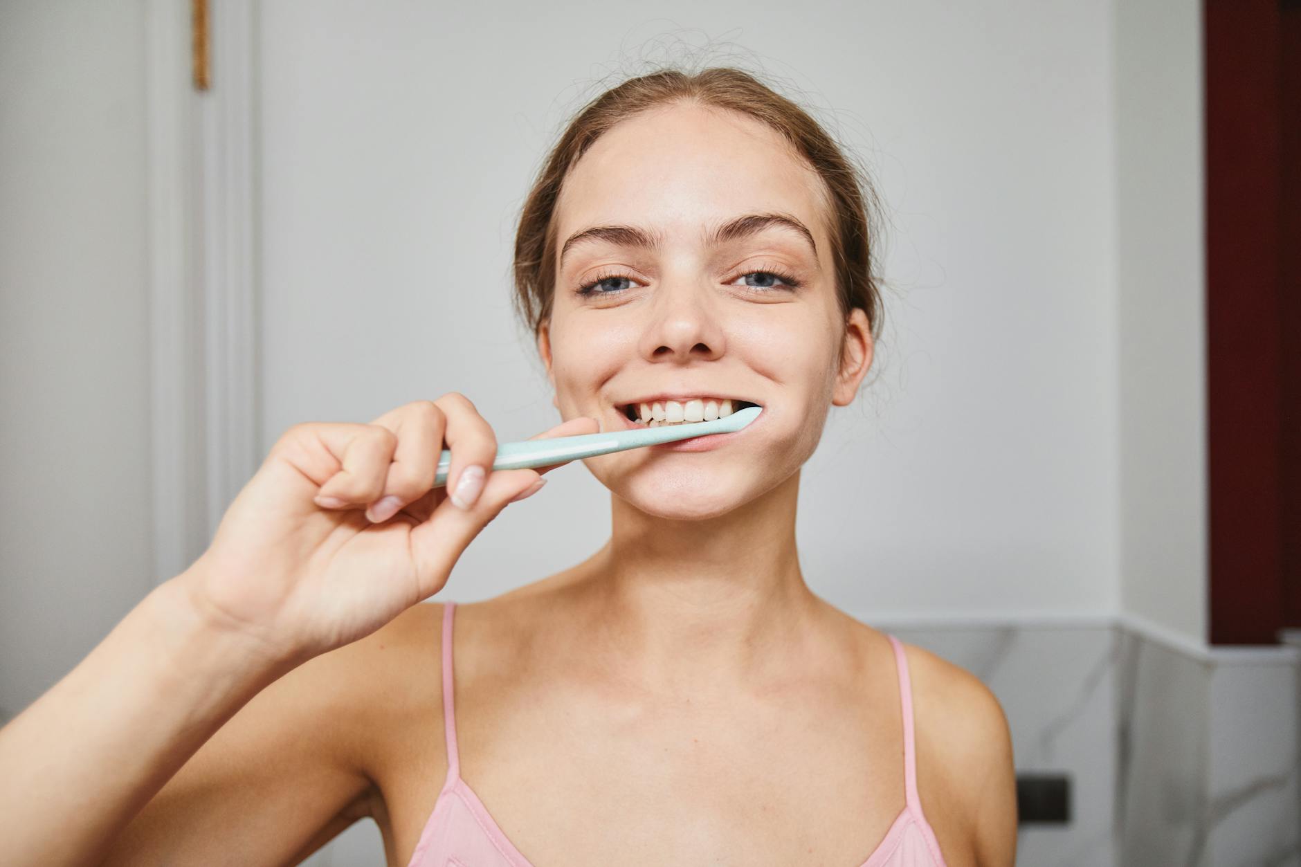 Woman brushing teeth — Atrium Scientific contract manufactures toothpastes, dental gels, and oral care products for consumer brands